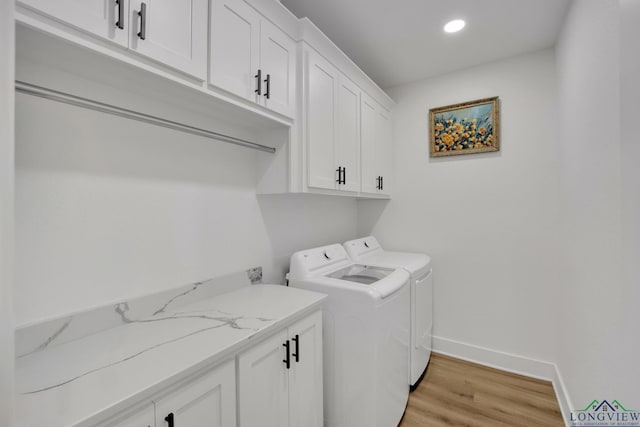 laundry room with light hardwood / wood-style flooring, washer and clothes dryer, and cabinets