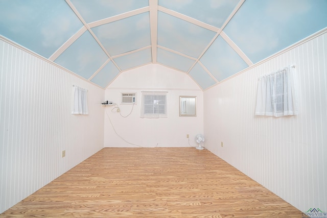 interior space with a wall mounted AC, wood-type flooring, and vaulted ceiling