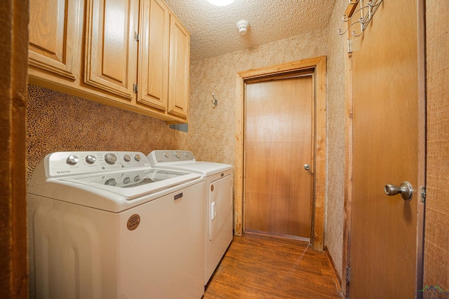 clothes washing area featuring a textured ceiling, washer and dryer, cabinets, and dark wood-type flooring