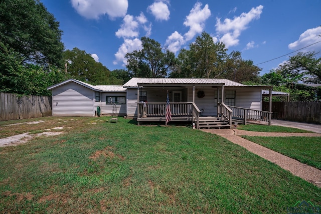 view of front of home with metal roof, a porch, a front yard, and fence