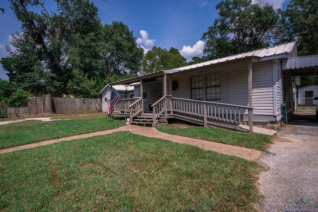 view of front of house with metal roof, covered porch, a front lawn, and fence