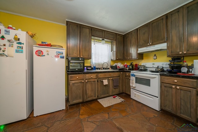 kitchen with under cabinet range hood, white appliances, dark countertops, and a sink