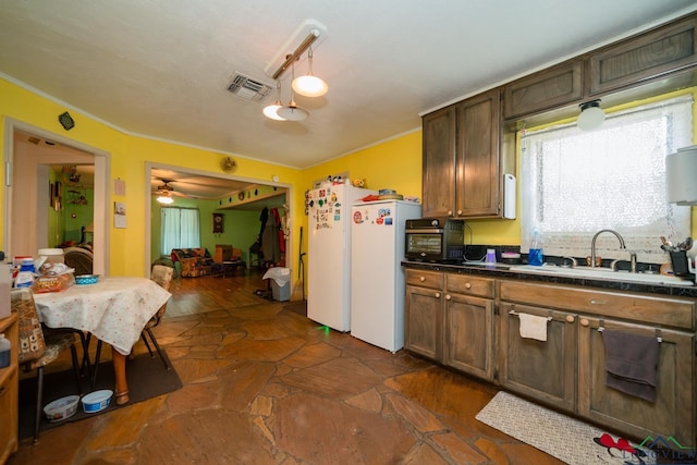 kitchen with dark countertops, visible vents, ornamental molding, freestanding refrigerator, and a sink