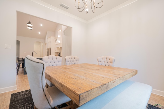 dining space with light hardwood / wood-style flooring, an inviting chandelier, and ornamental molding