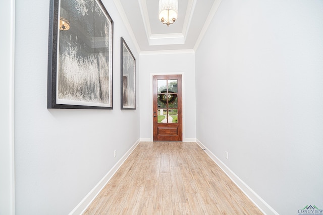 doorway featuring a raised ceiling, crown molding, light hardwood / wood-style flooring, and a notable chandelier