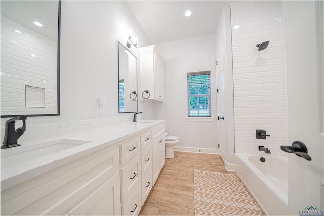 full bathroom with hardwood / wood-style floors, vanity, toilet, and tiled shower / bath combo