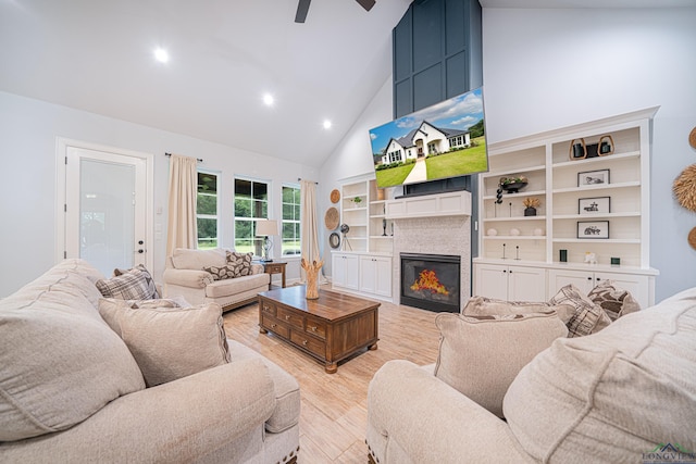 living room featuring ceiling fan, a large fireplace, high vaulted ceiling, and light hardwood / wood-style floors