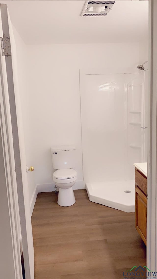 bathroom with a shower, vanity, wood-type flooring, and toilet