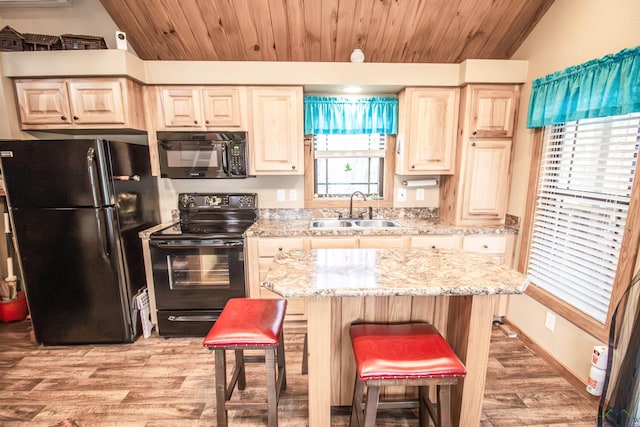 kitchen featuring light stone countertops, sink, lofted ceiling, a breakfast bar, and black appliances