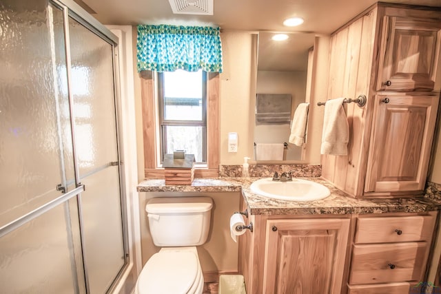 bathroom featuring toilet, vanity, and walk in shower