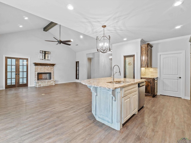 kitchen featuring a center island with sink, lofted ceiling with beams, sink, decorative backsplash, and light stone countertops