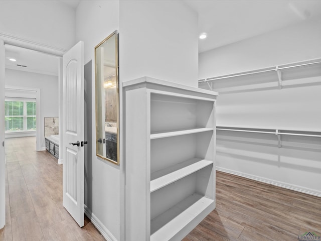 walk in closet with light hardwood / wood-style flooring