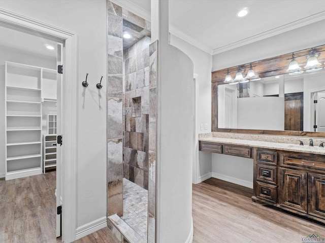 bathroom featuring vanity, wood-type flooring, ornamental molding, and walk in shower