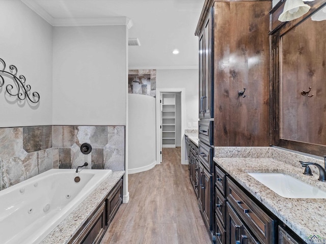 bathroom with crown molding, hardwood / wood-style floors, a bathtub, vanity, and tile walls