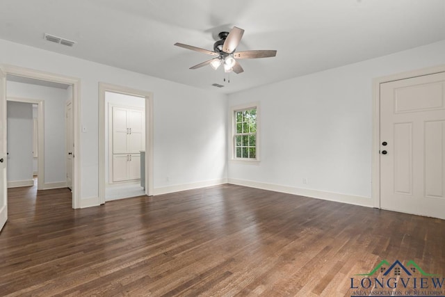 spare room with ceiling fan, visible vents, baseboards, and dark wood-type flooring