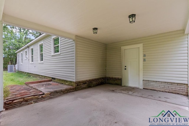 view of exterior entry with central AC unit and a patio area