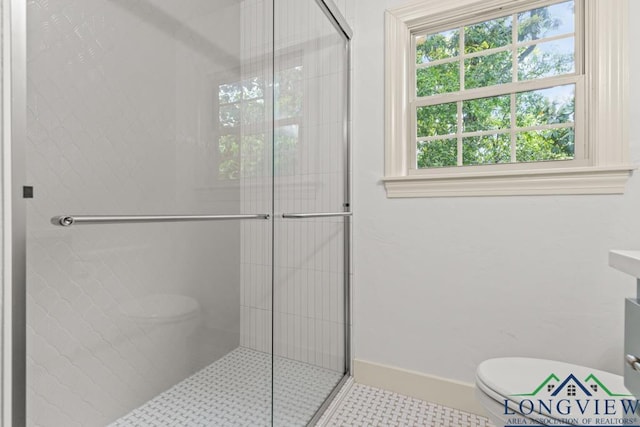 bathroom with baseboards, toilet, and a shower stall