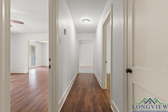 hallway with dark wood-type flooring and baseboards