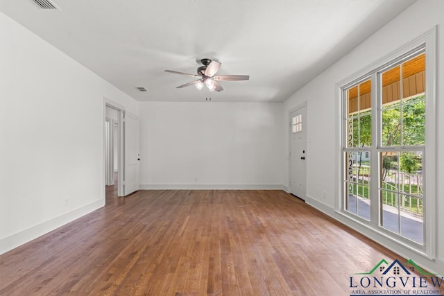 unfurnished room featuring baseboards, a ceiling fan, wood finished floors, and visible vents