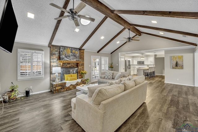 living room featuring dark hardwood / wood-style floors, vaulted ceiling with beams, ceiling fan, a brick fireplace, and a textured ceiling