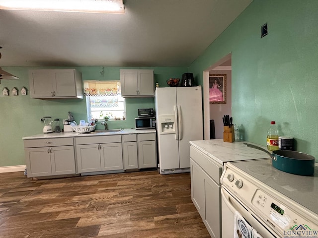 kitchen with dark wood-type flooring, white appliances, washer / dryer, and sink