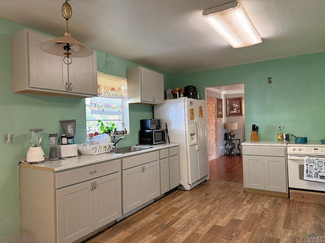 kitchen featuring pendant lighting, white cabinetry, sink, light wood-type flooring, and white appliances