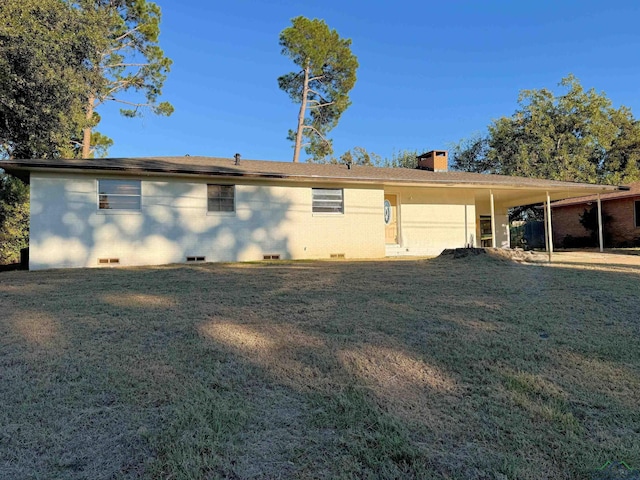 back of property with a carport and a lawn