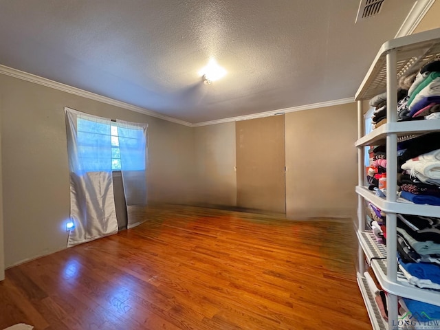 empty room featuring crown molding, wood-type flooring, and a textured ceiling