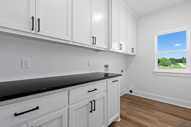 washroom featuring wood finished floors, baseboards, hookup for a washing machine, electric dryer hookup, and cabinet space
