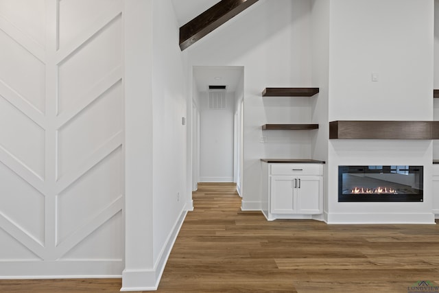 interior space featuring beamed ceiling, baseboards, visible vents, and wood finished floors