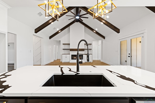 kitchen featuring an inviting chandelier, beam ceiling, a sink, open floor plan, and visible vents