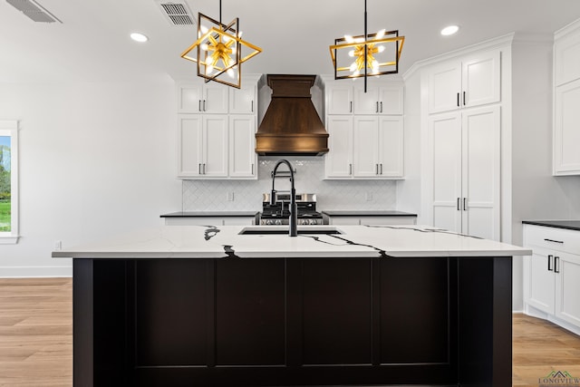 kitchen featuring visible vents, backsplash, custom exhaust hood, and an inviting chandelier