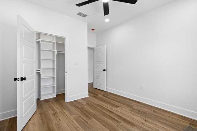 unfurnished bedroom featuring baseboards, a closet, wood finished floors, and visible vents