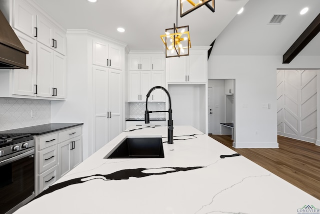kitchen featuring stainless steel gas stove, recessed lighting, wood finished floors, custom range hood, and pendant lighting