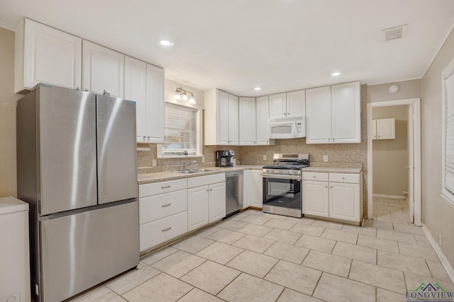 kitchen featuring backsplash, sink, light stone countertops, white cabinetry, and stainless steel appliances