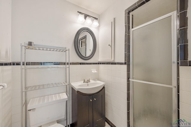 bathroom featuring vanity, a shower with door, toilet, and tile walls