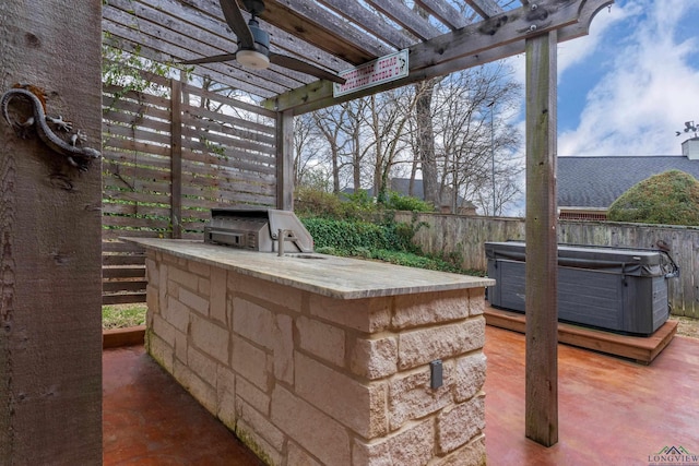 view of patio / terrace with a hot tub, ceiling fan, fence, exterior kitchen, and a pergola