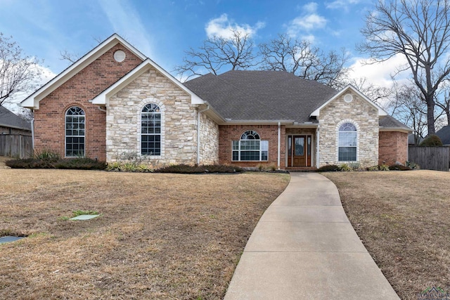 ranch-style house with fence, a front lawn, and brick siding