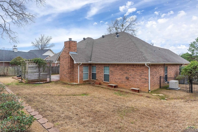 rear view of house with a yard, brick siding, and fence