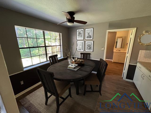 dining space with ceiling fan, dark wood-type flooring, and a textured ceiling