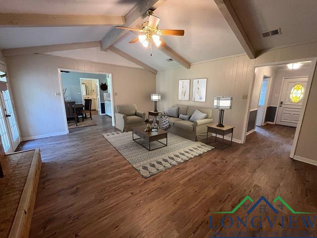 unfurnished living room featuring vaulted ceiling with beams, ceiling fan, and dark hardwood / wood-style flooring