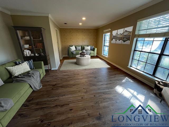 living room with a wealth of natural light, dark wood-type flooring, and ornamental molding