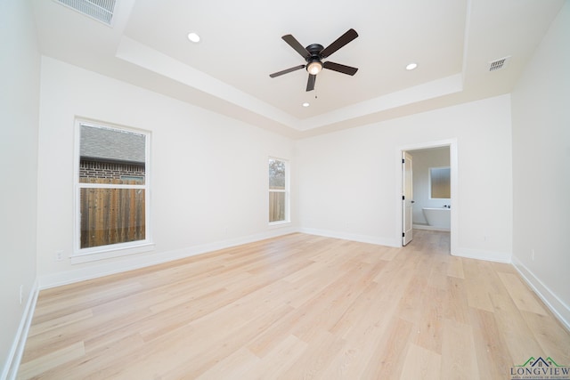 unfurnished room featuring a tray ceiling, light hardwood / wood-style flooring, and ceiling fan