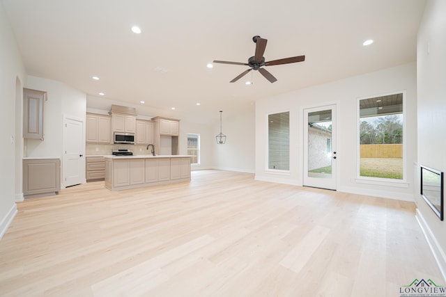 unfurnished living room with plenty of natural light, sink, and light hardwood / wood-style flooring