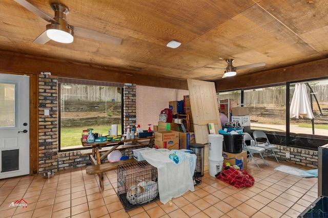 interior space featuring ceiling fan, light tile patterned floors, wood ceiling, and brick wall