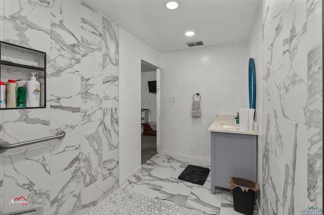 bathroom featuring vanity and tile walls