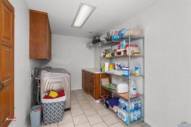 laundry area featuring washer and dryer, light tile patterned floors, and cabinets