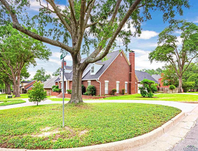 5908 Regents Row, Tyler, TX 75703 - traditional-style house featuring a chimney, brick siding, curved driveway, and a front lawn