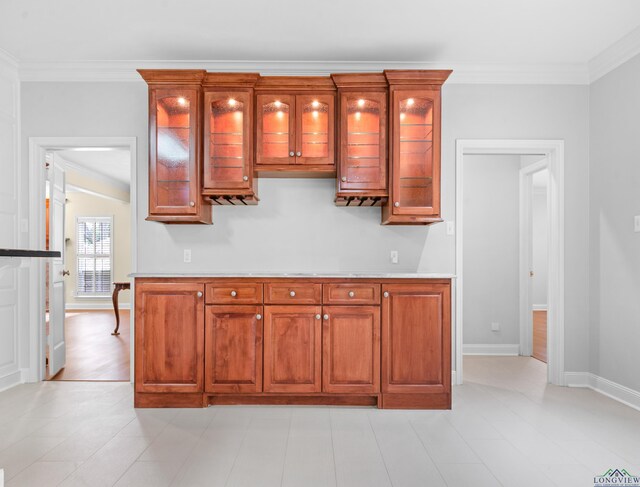 5908 Regents Row, Tyler, TX 75703 - kitchen featuring ornamental molding, glass insert cabinets, baseboards, light countertops, and brown cabinetry