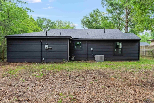 rear view of house featuring fence, roof with shingles, and central air condition unit